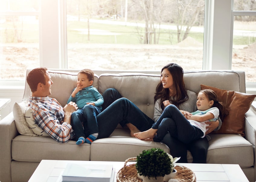 family of 4 sitting/laying on couch together talking and laughing